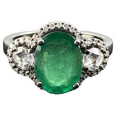 A beautiful 3.01 carat oval cut emerald ring, with 0.30 carats rose cut side stone diamonds and 0.30 carats of full cut diamond halo. The emerald center stone is transparent with a beautiful vivid green color, and all the gemstones are set in solid 18K gold with black rhodium polish, giving the ring an Art Deco look. Currently sized at US7, can be resized. We provide free shipping, and accept returns. Please feel free to message us for more information. Oval Emerald Ring With Single Cut Diamonds, Oval Emerald Ring With Diamond Accents, Oval Emerald Ring With Rose Cut Diamonds, Green Oval Diamond Ring With Single Cut, Green Oval Single Cut Diamond Rings, Oval Emerald Ring With Single Cut Diamonds For Anniversary, Classic Oval Emerald Ring With Single Cut Diamonds, Oval Emerald Ring With Rose Cut Diamonds For Anniversary, Anniversary Oval Emerald Ring With Rose Cut Diamonds