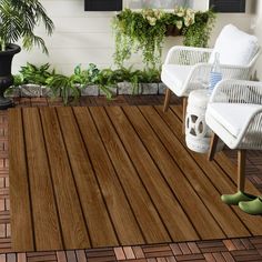 a wooden deck with chairs and potted plants