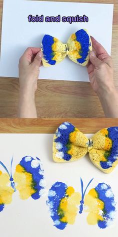 two hands are holding up small yellow and blue bow ties to paint on the paper