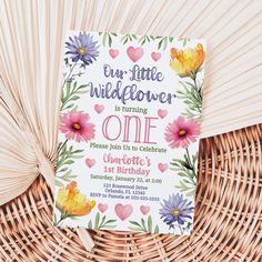 a little wildflower is turning one birthday card on a wicker basket with flowers