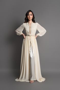 The Lou caftan is an elegant and sophisticated set. Composed of pants in fluid and comfortable ivory silk satin, as well as a matching overcoat in ivory chiffon with embroidered and gold finishes on the bust. Matching belt and decorated with a flower in the center. Elegant Cream Long Sleeve Abaya, Elegant Long Sleeve Cream Abaya, Elegant Beige Abaya For Eid, Elegant Evening Thobe In Maxi Length, Elegant Cream Abaya For Wedding, Elegant Gold Floor-length Thobe, Elegant Gold Maxi Length Abaya, Elegant Silk Maxi Abaya, Elegant Formal Kaftan For Eid