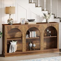 a wooden shelf with books and vases sitting on top of it next to stairs