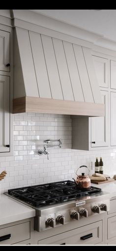 a stove top oven sitting inside of a kitchen next to white cabinets and counter tops