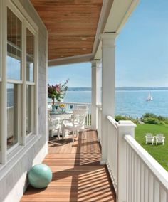 a porch with chairs and tables on the side of it next to an ocean view