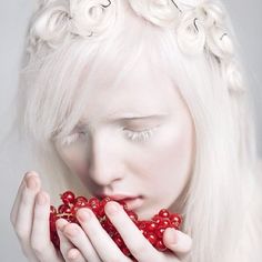 a woman with white hair and red berries in her hands