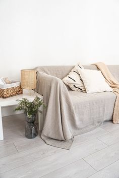 a couch with a blanket on top of it next to a table and potted plant