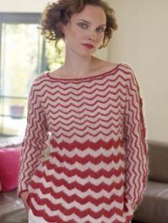 a woman standing in front of a couch wearing a red and white knitted sweater