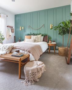 a bed room with a neatly made bed next to a table and two plants on the wall