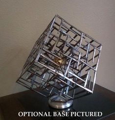 a metal object sitting on top of a wooden table next to a white wall with the words optical base pictures