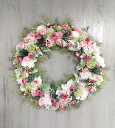 a wreath with pink and white flowers hanging on a wall