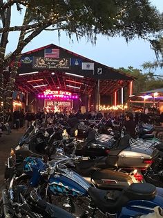 a large group of motorcycles parked in front of a concert venue with lights on the roof