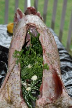 a large piece of meat sitting on top of a table covered in vegetables and herbs