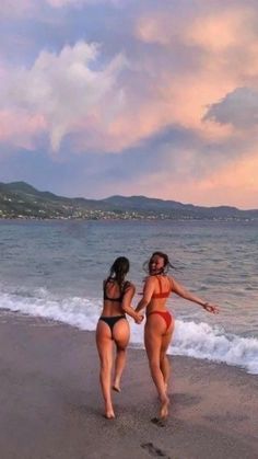 two women in bikinis walking on the beach