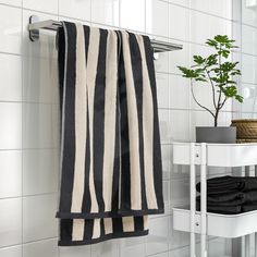 a black and white striped towel hanging on the wall next to a table with a potted plant