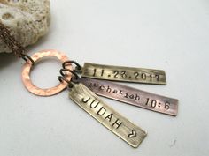 three personalized hand stamped necklaces on a table next to a piece of rock