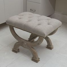 a bench sitting on top of a white tile floor next to a cabinet and drawers