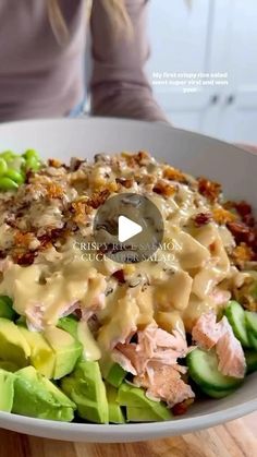 a woman sitting at a table in front of a plate of food that includes pasta, lettuce and meat