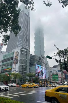 a city street filled with lots of traffic and tall buildings in the background on a cloudy day