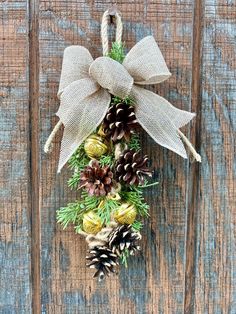 a wreath with pine cones and bells hanging on a wooden door