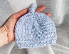 a hand is holding a blue knitted hat