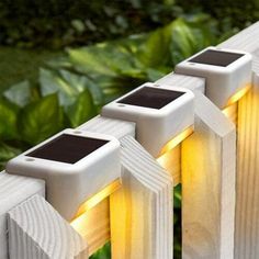 three solar powered lights on the side of a fence