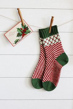 two christmas stockings hanging on a clothes line with a card and wooden pegs attached to them