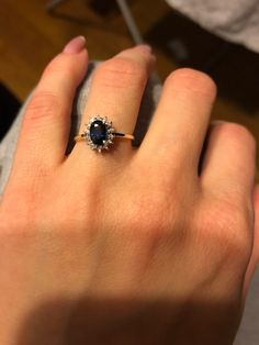 a woman's hand with a ring on it that has a blue stone in the middle