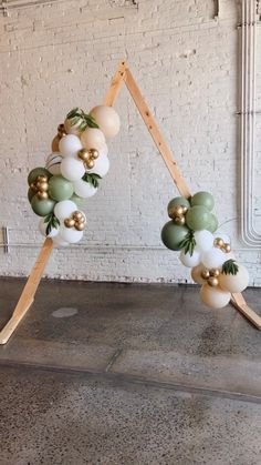 a sculpture made out of balloons and wooden sticks on top of a cement floor next to a white brick wall