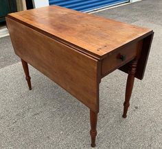 an old wooden desk sitting on top of a cement floor next to a blue garage door