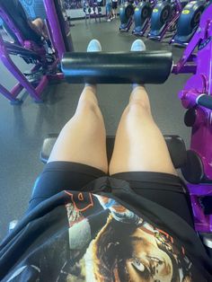 the legs of a woman who is sitting on a bench with a barbell in front of her