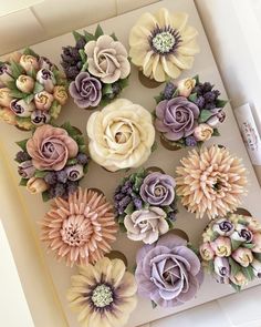 a box filled with lots of fake flowers on top of a white countertop next to a marker