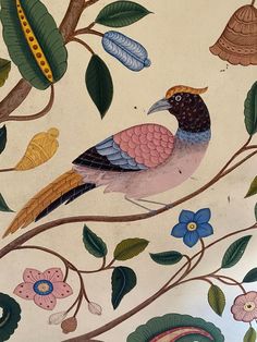 a bird sitting on top of a tree branch with leaves and flowers painted on it