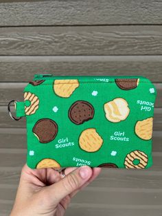 a hand holding up a small green purse with cookies and biscuits printed on the front