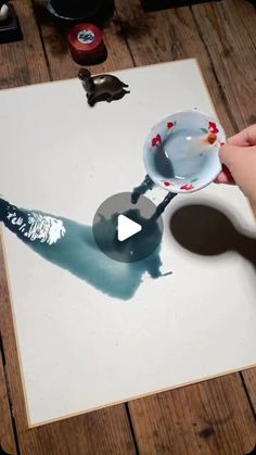 a person is using a spoon to paint an image on a piece of white paper