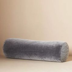 a large gray pillow sitting on top of a white table next to a brown wall