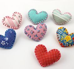 six heart shaped fabric magnets on a white surface