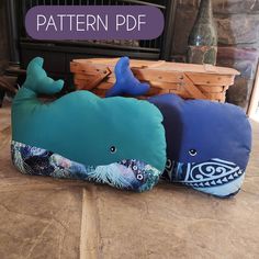 two stuffed whale pillows sitting next to each other on a table with a fireplace in the background