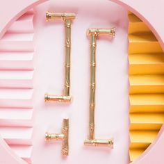 the letters t and l are made out of gold bamboo sticks on a pink background