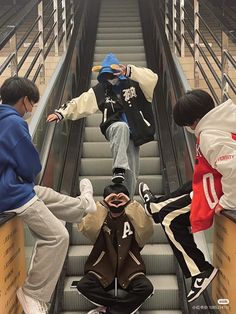 three boys are sitting on an escalator and one boy is standing in the middle