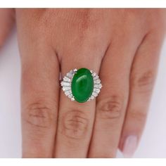 5.32 carats of true green untreated jadeite jade are displayed as the focal point of this beautiful piece. This ballerina style ring features a platinum band with delicate filigree, the lush green oval cut gemstone rests proudly at its head. 16 brilliantly shining baguette cut diamonds hug the center stone, 8 on each side, totaling 1.34 carats.   The center stone is HK Stone and Lab Certified. It's a Fei Cui Grade A untreated Jadeite Jade.   Details: Item Type: Ballerina Ring Metal: Platinum 900 Size: 6 1/4 Weight: 8.80 Grams Setting: Cathedral, Filigree  Center Stone Details: Stone Type: Untreated Jadeite Jade (Fei Cui) Grade: A  Carat: 5.32 Cut: Oval Cabochon Color: Intense Green Treatment: None Measurements: 16.09 x 10.30 x 3.60 MM   Hong Kong Jade & Stone Laboratory Certified  Side Sto Ballerina Ring, Ballerina Style, Green Oval, Baguette Cut Diamond, Ring Metal, Jade Stone, Baguette Cut, Diamond Jewellery, Lush Green