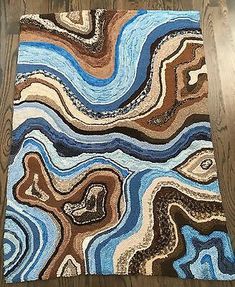 a rug on the floor that is made out of wood and has different colored waves