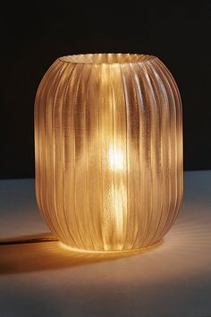 a glass vase sitting on top of a table next to a light that is turned on