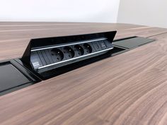 a wooden table with an electrical outlet in the middle and four surge protectors attached to it