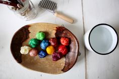 a wooden plate topped with gummy bears next to a white cup and brush on top of a table