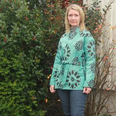 a woman standing in front of some bushes