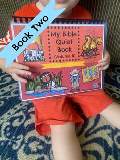 a young boy holding up a book with the title my bible quiet book