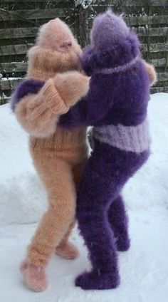 two stuffed animals standing in the snow with their hands on each other's backs