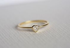 a gold ring with a heart shaped diamond in the center on a white surface,