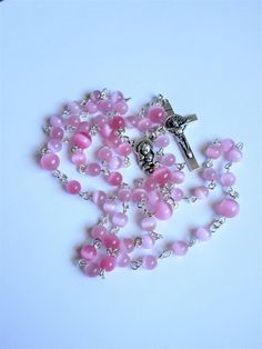 "This pink cat's eye Catholic rosary is a special gift for a girl for First Communion or any other occasion. It is a complete 5 decades. The body of the rosary is 27\" around with a 5 inch cross drop. The silver plated links are hand turned. The rosary parts are oxidized silver made in Italy. This rosary will be slipped into a velvet bag and shipped in a bubble mailer." Handmade Pink Cross Rosary, Handmade Pink Rosary With Cross, Handmade Pink Rosary With Round Beads, Pink Rosary With 8mm Round Beads, Handmade Pink Spiritual Rosary, Catholic Rosary, Rosary Necklace, The Rosary, Rosary Catholic