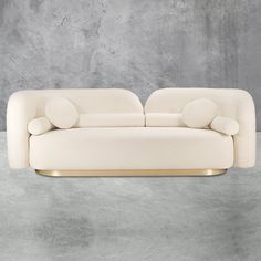 a white couch sitting on top of a cement floor next to a gray concrete wall